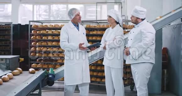 有魅力的女人面包师和她的同事面包师和一位老男人的工程师就使用规则进行了交谈视频的预览图