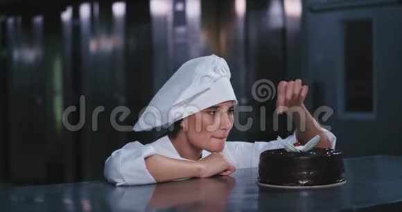 年轻漂亮的面包师小姐把樱桃从巧克力蛋糕上摘下来高兴地笑着放进嘴里视频的预览图