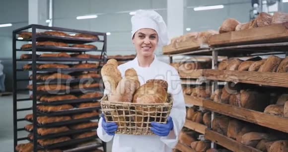 微笑的女人面包师的肖像带着一个老式的大篮子带着一个新鲜的面包直视着相机有一个视频的预览图