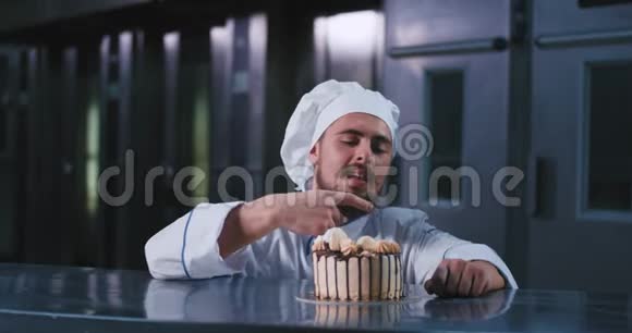 一个英俊的胖乎乎的男人穿着厨师的服装留着长长的胡须用手指摘着这个生日蛋糕看上去很开心视频的预览图