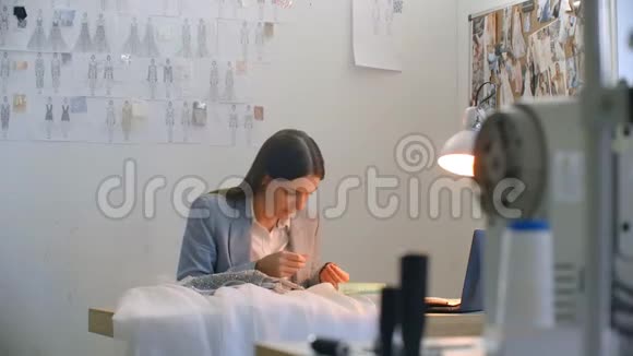 一位年轻的女设计师在工作室里做一件连衣裙裁缝工作室缝制珠子和珠宝裁缝视频的预览图