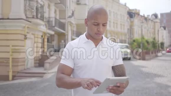 英俊秃顶的中东商人在城市街道上的平板电脑上打字自由职业概念工作人员视频的预览图