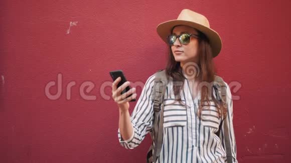 使用智能手机在红墙前拍摄的时髦女游客画像视频的预览图