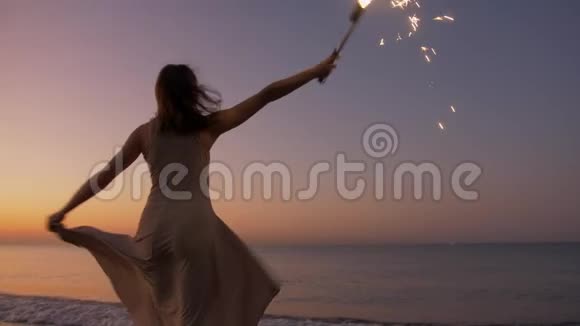 快乐健康浪漫的女人带着烟火在海滩上盘旋视频的预览图