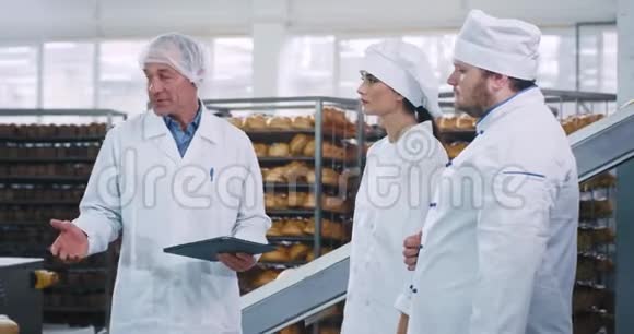 会议时间在面包店工厂老人工程师与一个性能平板说明使用工业规则视频的预览图