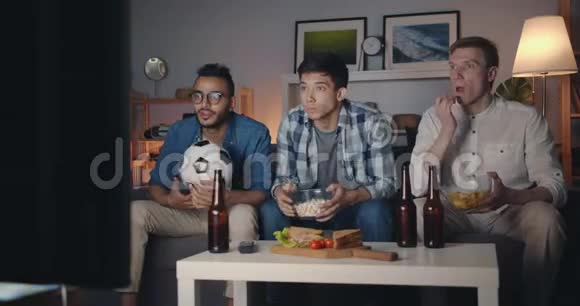 帅哥在电视上看足球比赛吃零食庆祝胜利视频的预览图