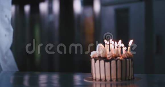 一位年轻漂亮的女士戴着蓝色手套穿着炊具制服吹灭了蛋糕上的蜡烛视频的预览图