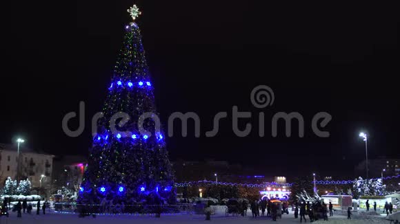 在城市的中心广场上装饰着花环和灯光的圣诞树在夜间发光新年前夜视频的预览图