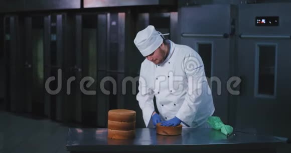 一位年轻的胖乎乎的厨师把一个蛋糕切成两半而他旁边还有三个蛋糕和一个视频的预览图