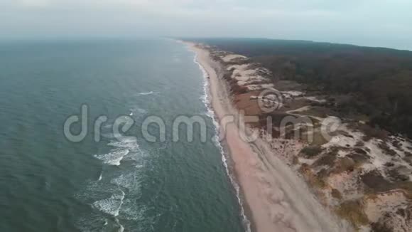 日落后蓝色小时的波罗的海海岸鸟瞰图暮光的海岸线带着滚滚的波浪空旷的海滩视频的预览图