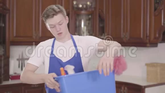 年轻英俊的疲惫的男人拿着篮子用洗涤剂用手擦着额头清洁日视频的预览图