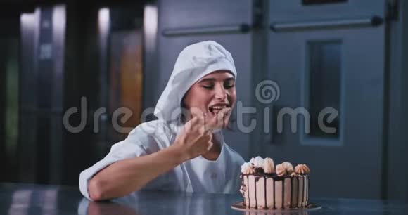 一位年轻的面包师女士在一家工业厨房的面包店里微笑着她品尝着新鲜烘焙蛋糕上的奶油视频的预览图
