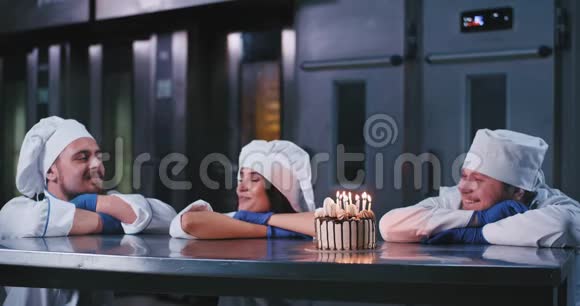 一个有魅力的女人吹灭了生日蛋糕上的蜡烛两个有魅力的男人和她在一起视频的预览图
