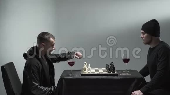 两个正在下棋的人坐在桌旁面前端着红酒杯摄影棚视频的预览图