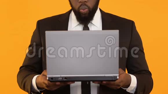 很高兴非裔美国人拿着笔记本电脑做着令人惊叹的手势商务电子邮件视频的预览图