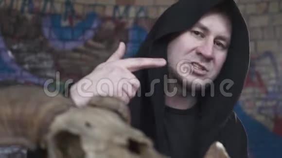 一个穿着黑色长袍头盖着的肖像人一边说话一边唱歌一边看着镜头拍摄一个剪辑视频的预览图