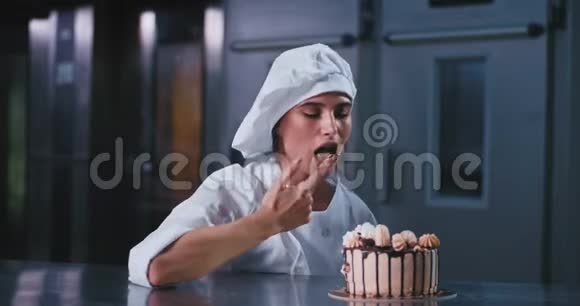 面包店的商业理念在一个有魅力的商业厨房里快乐的面包师女士用手指品尝蛋糕上的奶油视频的预览图