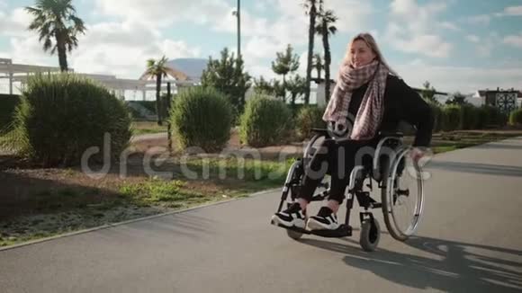 快乐的年轻女性轮椅使用者在阳光明媚的日子里在公园里散步视频的预览图
