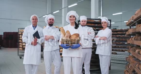 微笑魅力年轻的贝克女士和所有主要的面包师团队在面包店制造的中间直视视频的预览图