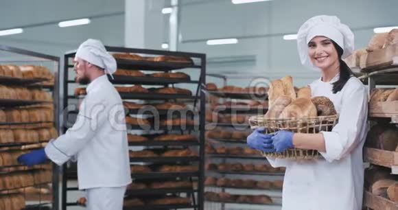 微笑着美丽的年轻面包师带着一篮子新鲜的烘焙面包直视着相机微笑着大块面包视频的预览图
