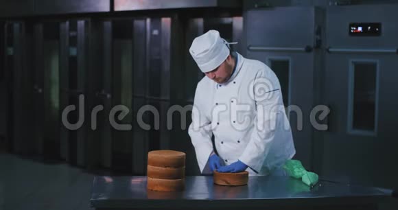 一个长得很帅的面包师穿着得体的厨师服装把蛋糕切成两半检查蛋糕的一致性视频的预览图