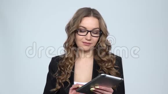 在工作室里一位穿着灰色背景的女士在平板上发短信慢动作视频的预览图