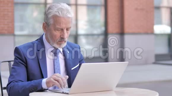 疲劳的老商人颈部疼痛在笔记本电脑上工作户外视频的预览图