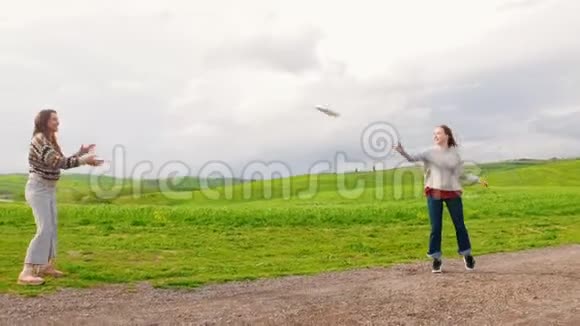 两个笑着的女人扔盘子在绿野上跳舞视频的预览图