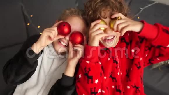 一对穿着睡衣的快乐孩子在卧室里玩得很开心玩着新年的球圣诞节准备视频的预览图