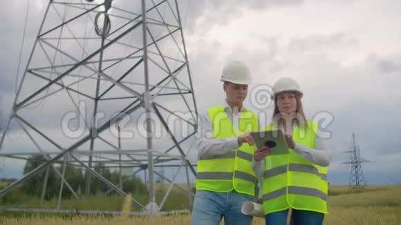 电力线路手里拿着平板电脑的男女工程师检查新塔的安装进度视频的预览图