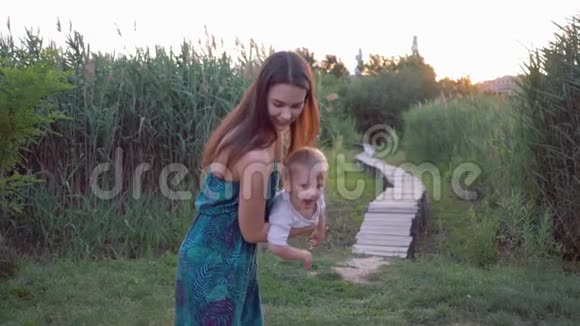 快乐的童年年轻开朗的妈妈和可爱的小男孩玩耍小男孩在妈妈的手中飞翔视频的预览图