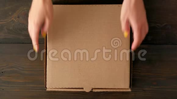 女性手打开盒子在木制背景上有甜甜圈视频的预览图