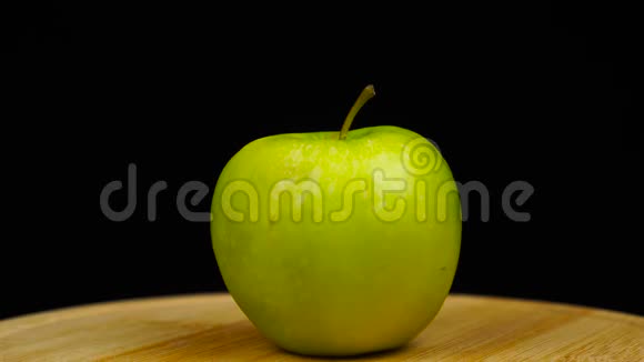 青苹果放在木板上旋转360度黑色背景视频的预览图