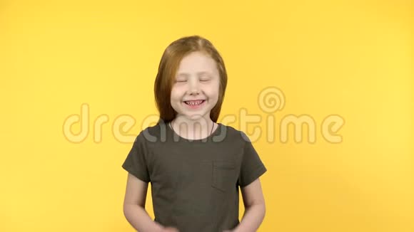 红发小孩害羞地笑着看着黄色背景的摄像机视频的预览图
