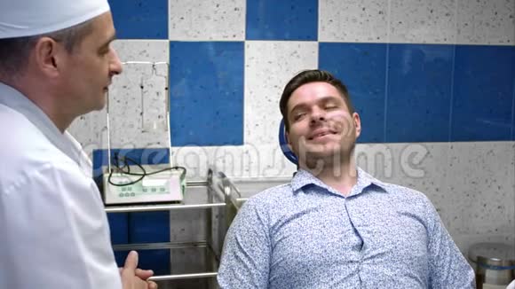 专业牙医与他的年轻男性病人在牙科诊所交谈视频的预览图