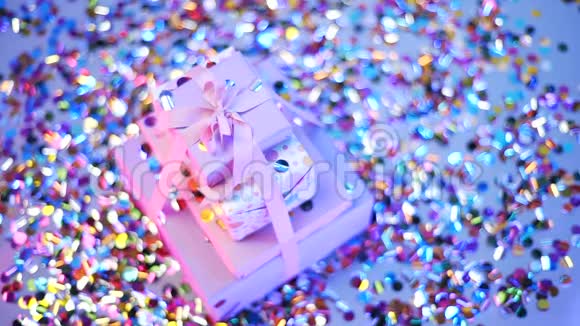 精美包装的礼物在霓虹灯中拍摄五颜六色的纸屑落在礼物上金属圆形五彩纸屑在视频的预览图