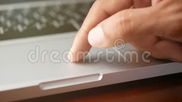 4K特写一个男人用手提笔记本电脑用手指用键盘和触摸板或触控板滑动和放大放大视频的预览图