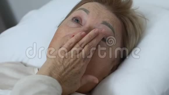 爱哭的老太太躺在家里的床上抑郁生活和健康问题视频的预览图