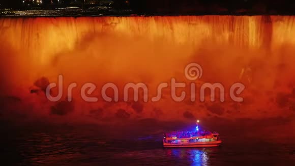 一艘带游客的船正漂浮在尼亚加拉瀑布的脚下晚上瀑布被泛光灯照亮视频的预览图