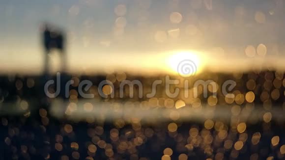 日落场景背景下车窗上的离焦波克雨滴视频的预览图