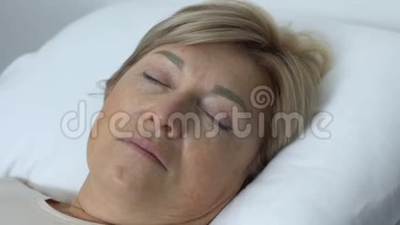 虚弱的老太太躺在床上睡后睁开眼睛康复中心视频的预览图