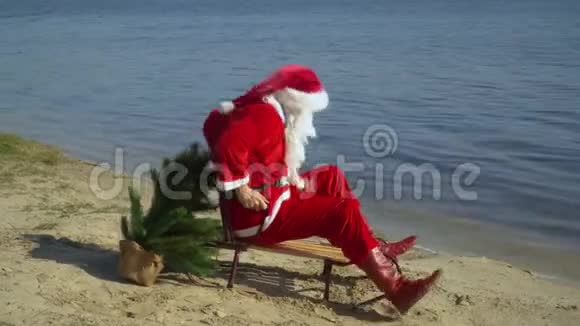 圣诞老人坐在湖沙岸上的雪橇上试图在靠近水的雪橇上前进圣诞老人视频的预览图