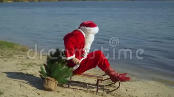 圣诞老人坐在沙滩上的雪橇上试图靠近水的雪橇前进视频的预览图