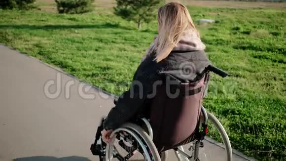 在阳光明媚的日子里女人用轮椅在户外活动后景视频的预览图