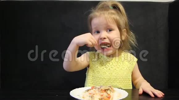 孩子们在黑桌上用勺子在黑色背景上吃煮熟的米饭和蘑菇视频的预览图