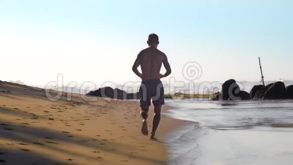 运动员在沙滩上奔跑迎着洁白的海浪视频的预览图