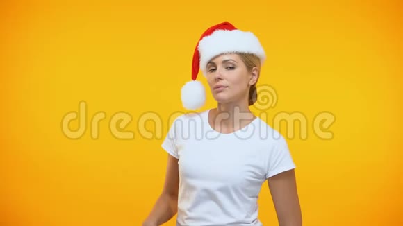 戴着圣诞帽的漂亮女人在明亮的背景上亲吻调情的姿态视频的预览图