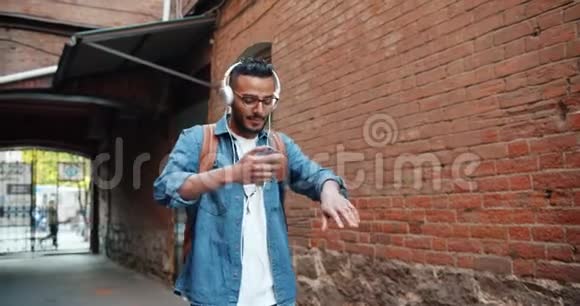阿拉伯人在户外用智能手机和耳机听音乐的慢动作视频的预览图