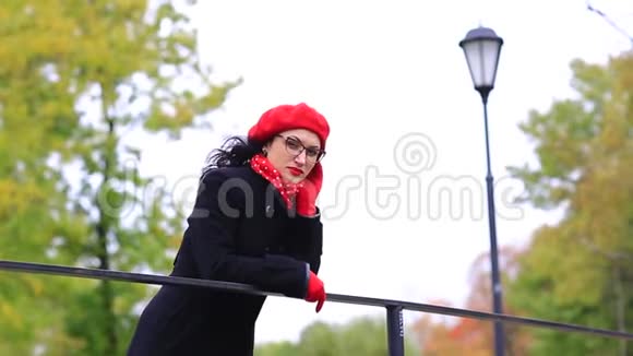 一个戴着红色贝雷帽和眼镜的女人站在桥上视频的预览图