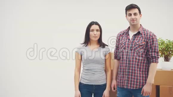 高兴的男人和女人站在新公寓里微笑着男人在展示钥匙女人在放弃拇指视频的预览图
